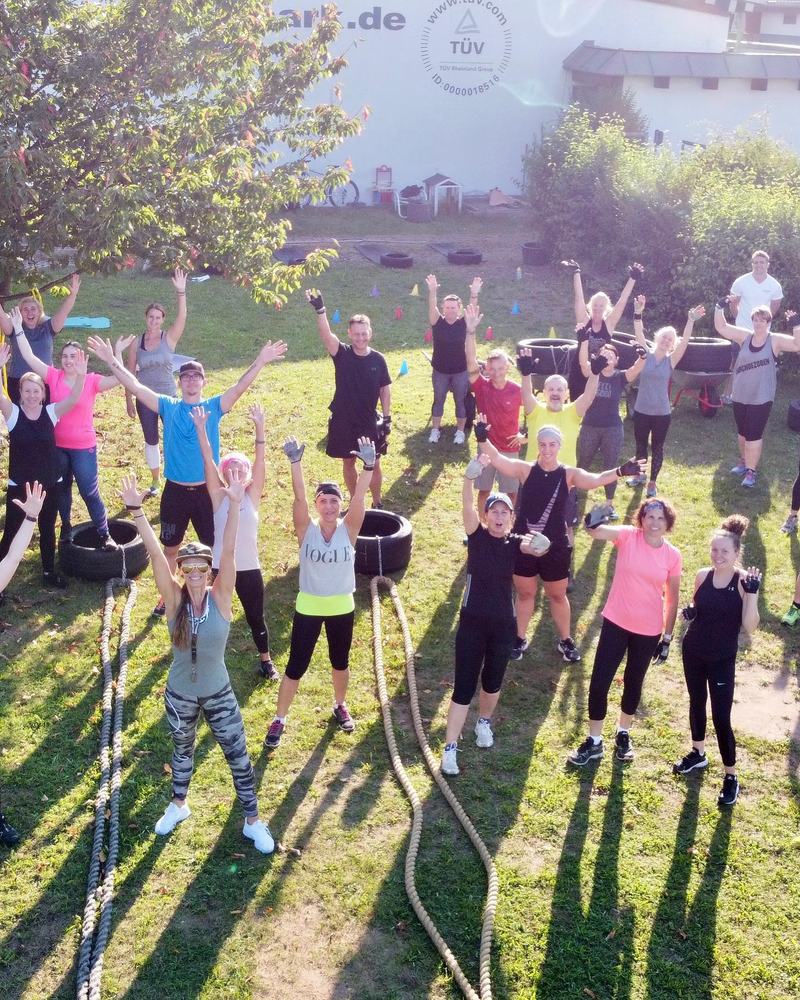 Bootcamp-Gruppe im Garten, alle Arme in der Luft