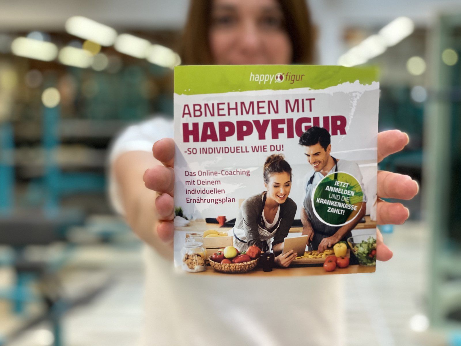 Iris hält den HappyFigur-Flyer in die Kamera: Das Online-Coaching mit deinem individuellen Ernährungsplan