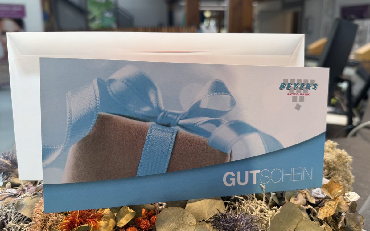 Gedruckter Gutschein des BEYERS AKTIV-PARK mit Geschenkmotiv, davor ein weißes Kuvert an der Rezeption