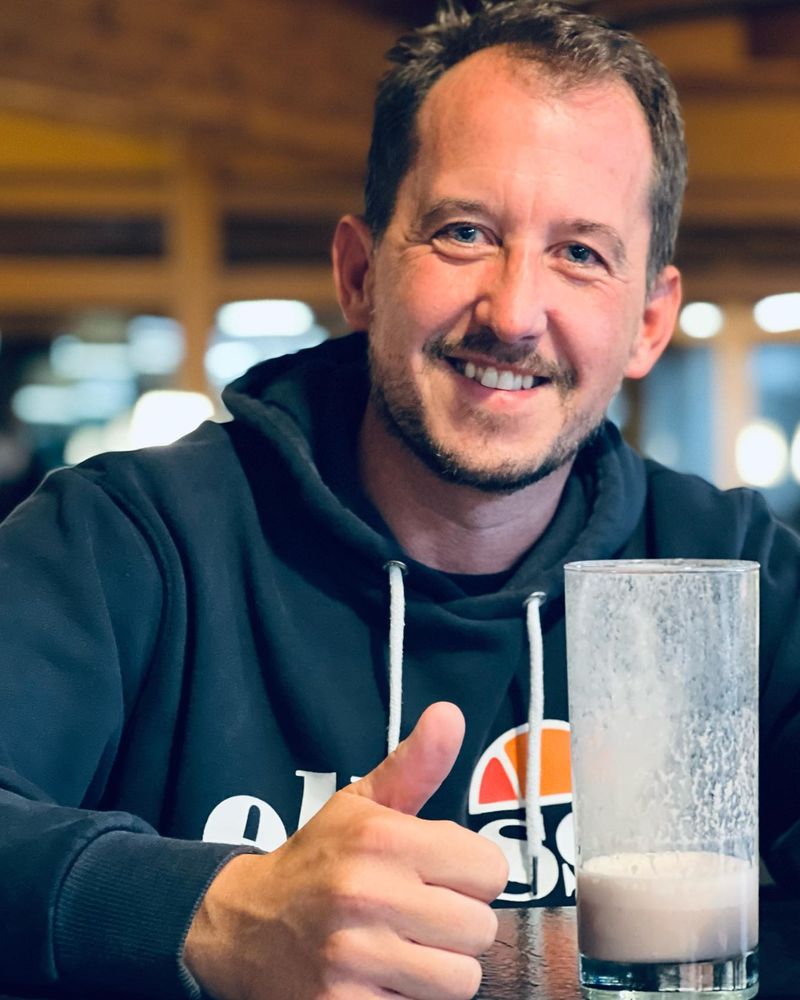 Mitglied mit Eiweißshake und Daumen hoch im Bistro