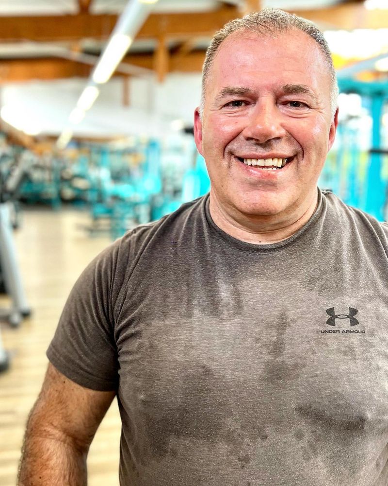 Mitglied lächelt an den Kurzhanteln in der Trainingshalle